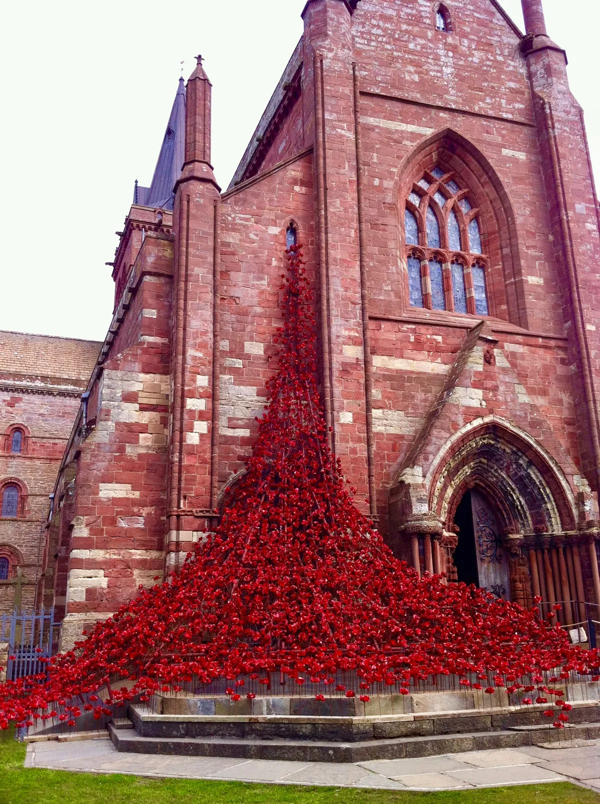 Art installation of poppies cascading from the top window of a church