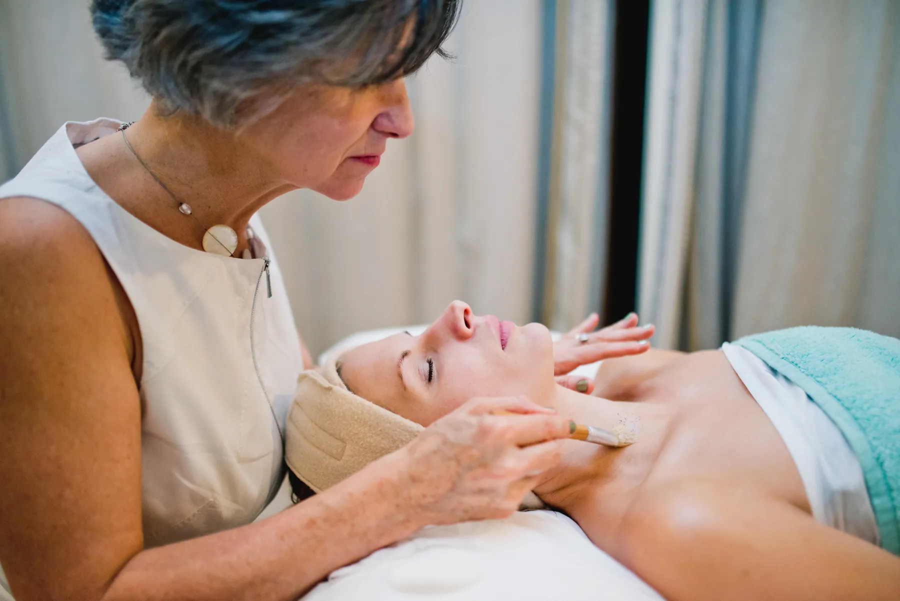 A Cotswold Spa therapist giving an organic facial by candlelight